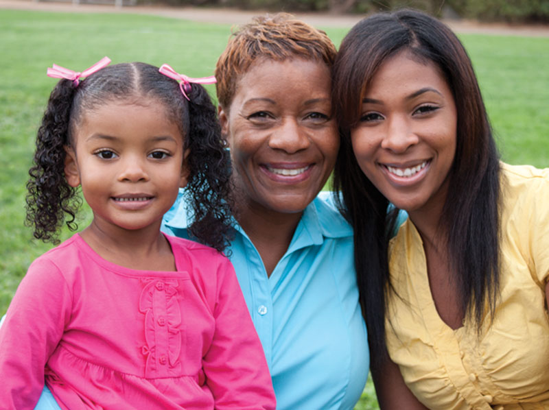 Grandmother, mother and daughter smiling.